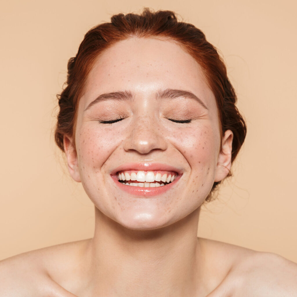 Amazing young redhead woman posing isolated over beige wall background. Portrait of a laughing pretty happy smiling amazing young redhead woman posing isolated over beige wall background.