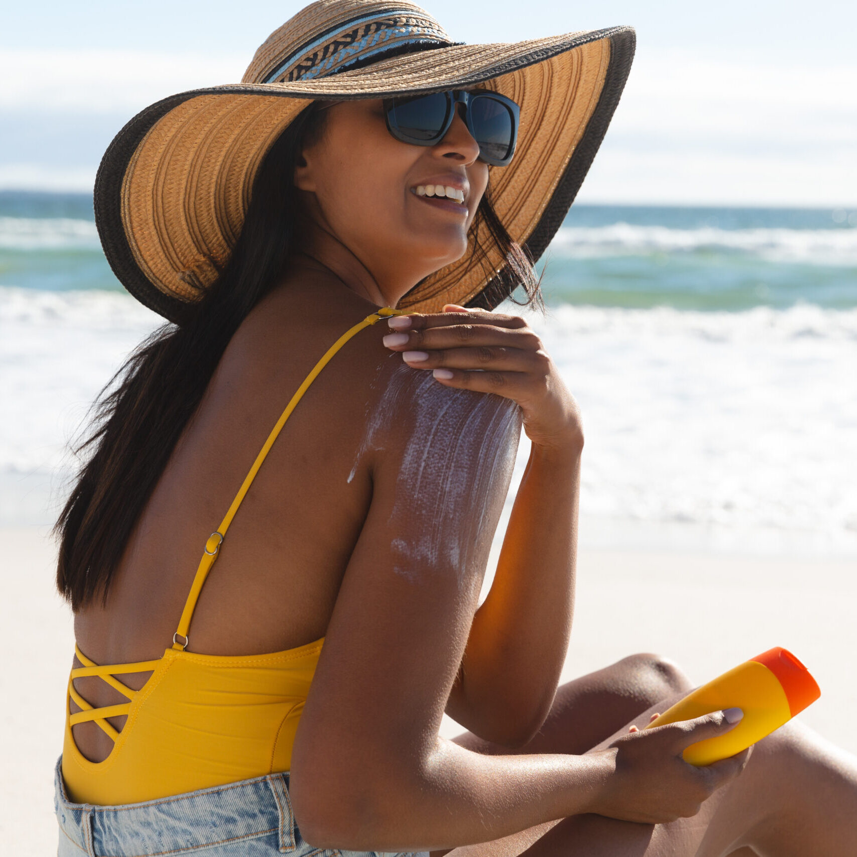 woman on the beach protecting her skin with spf sunscreen